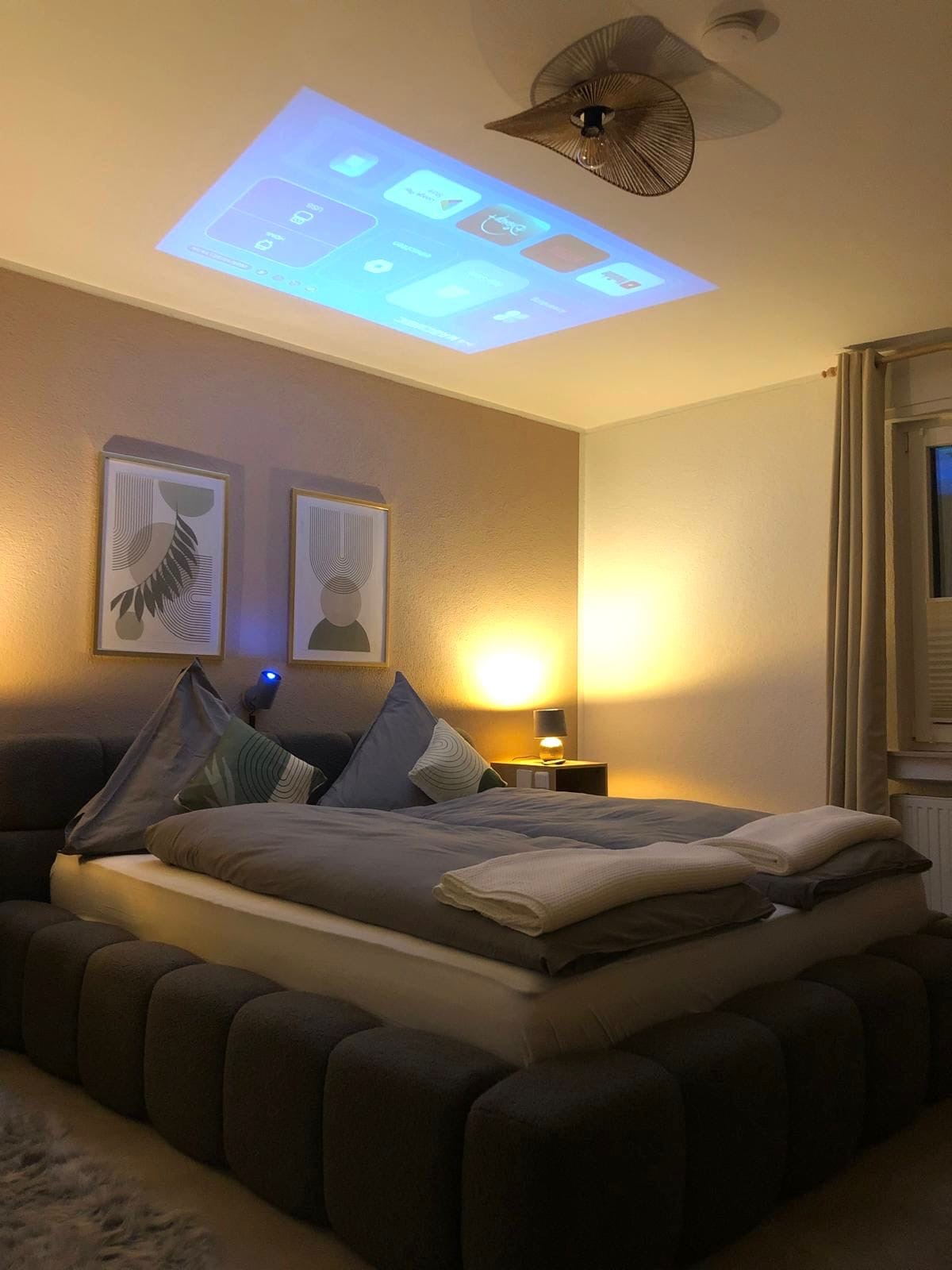 Schlafzimmer mit Beamer und Kingsize-Bett